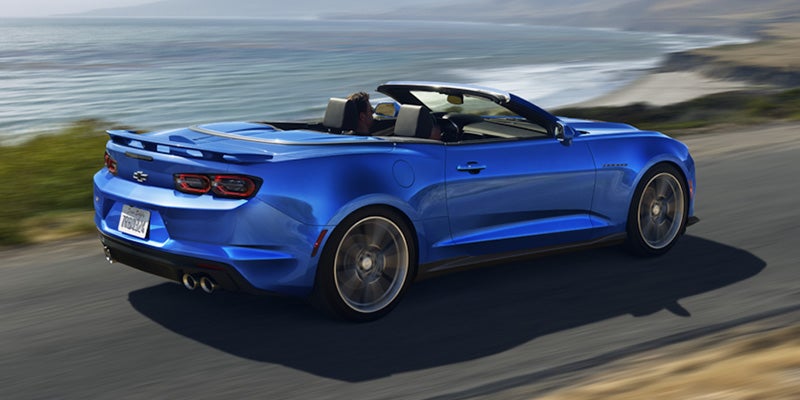 A blue 2024 Chevrolet Camaro Convertible driving on a coastal road.