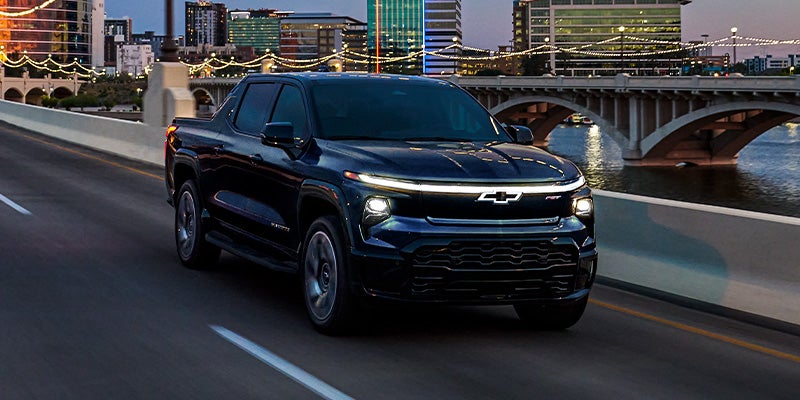 2024 Chevy Silverado EV Driving At Dusk On A City Bridge