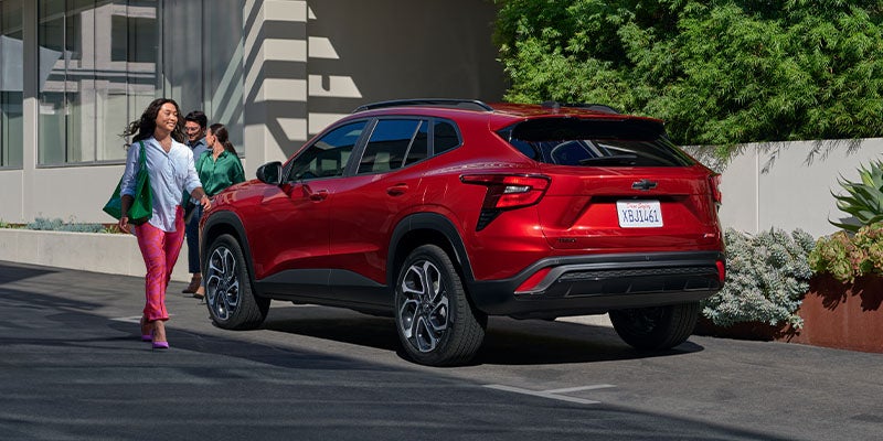 A woman approaching a Chevy Trax Parked in Front of an Office Building