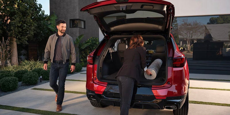A Woman Putting a Mat Inside the Trunk of a 2025 Red Chevy Blazer