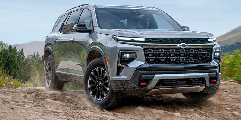 Low Three Quarters View of a 2025 Chevy Traverse on an Dirt Road Surrounded by Mountains