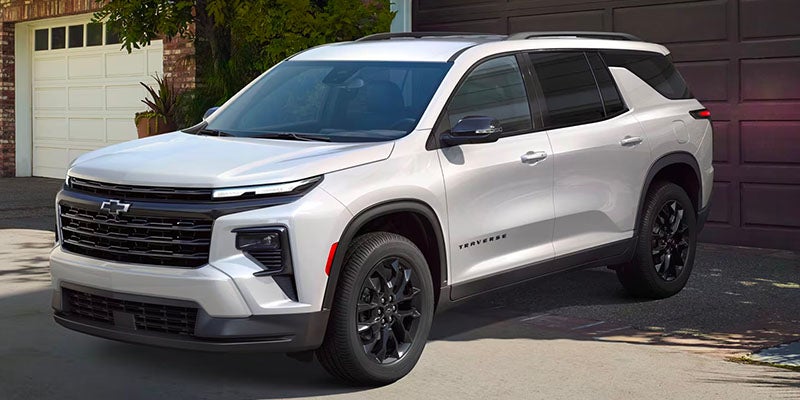 Three Quarters View of a 2025 White Chevy Traverse Coming Out of a Garage