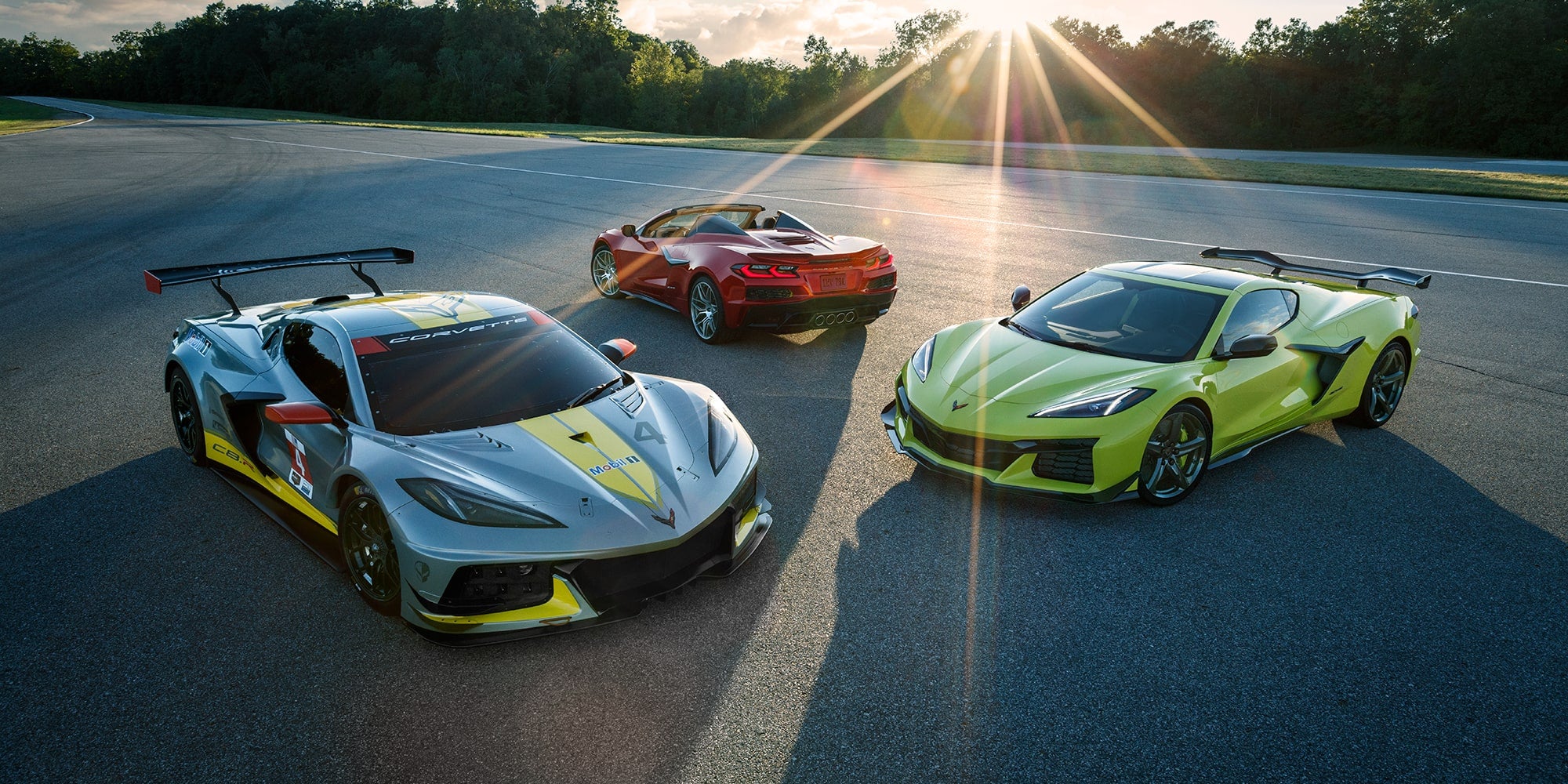 A Fleet of Corvette Z06s Sit on the Track with the Sun Setting in the Distance